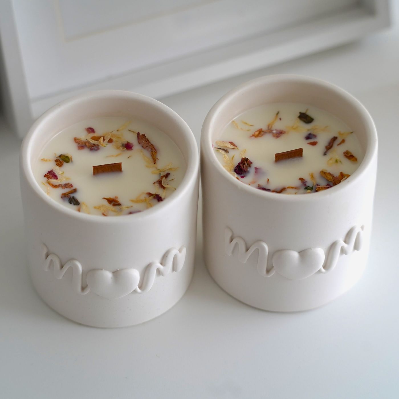 Vela artesanal de cera de soja en tarro de resina ecológica con la palabra "Mom" grabada. Vista desde arriba, se aprecia su superficie decorada con pétalos de flores secas, resaltando su delicado aroma floral y afrutado. Edición limitada para el Día de la Madre.